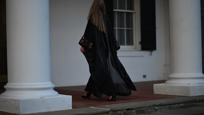 Person in a long black abaya walking past classical columns