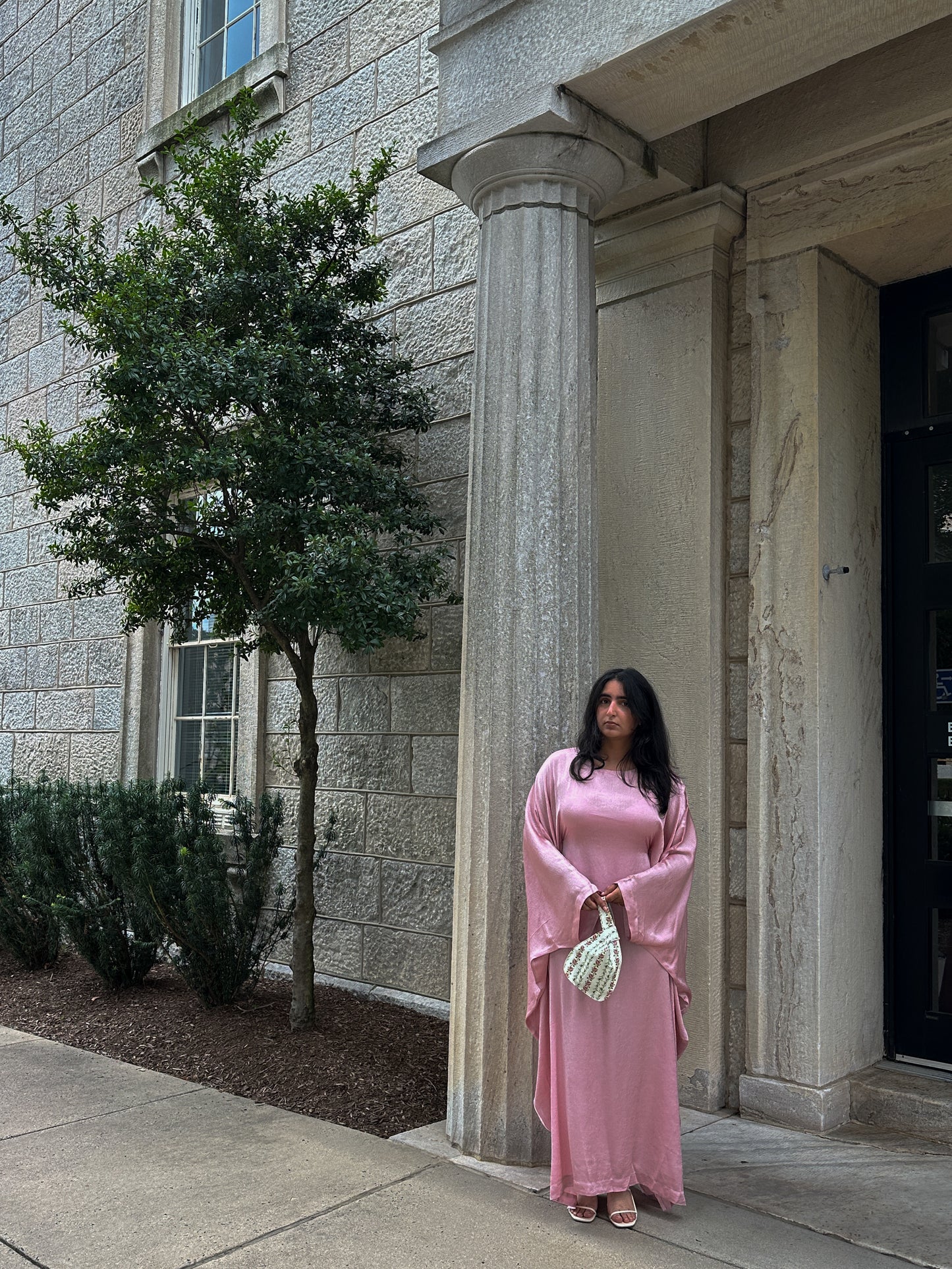 Woman in a pink dress standing outside a stone building