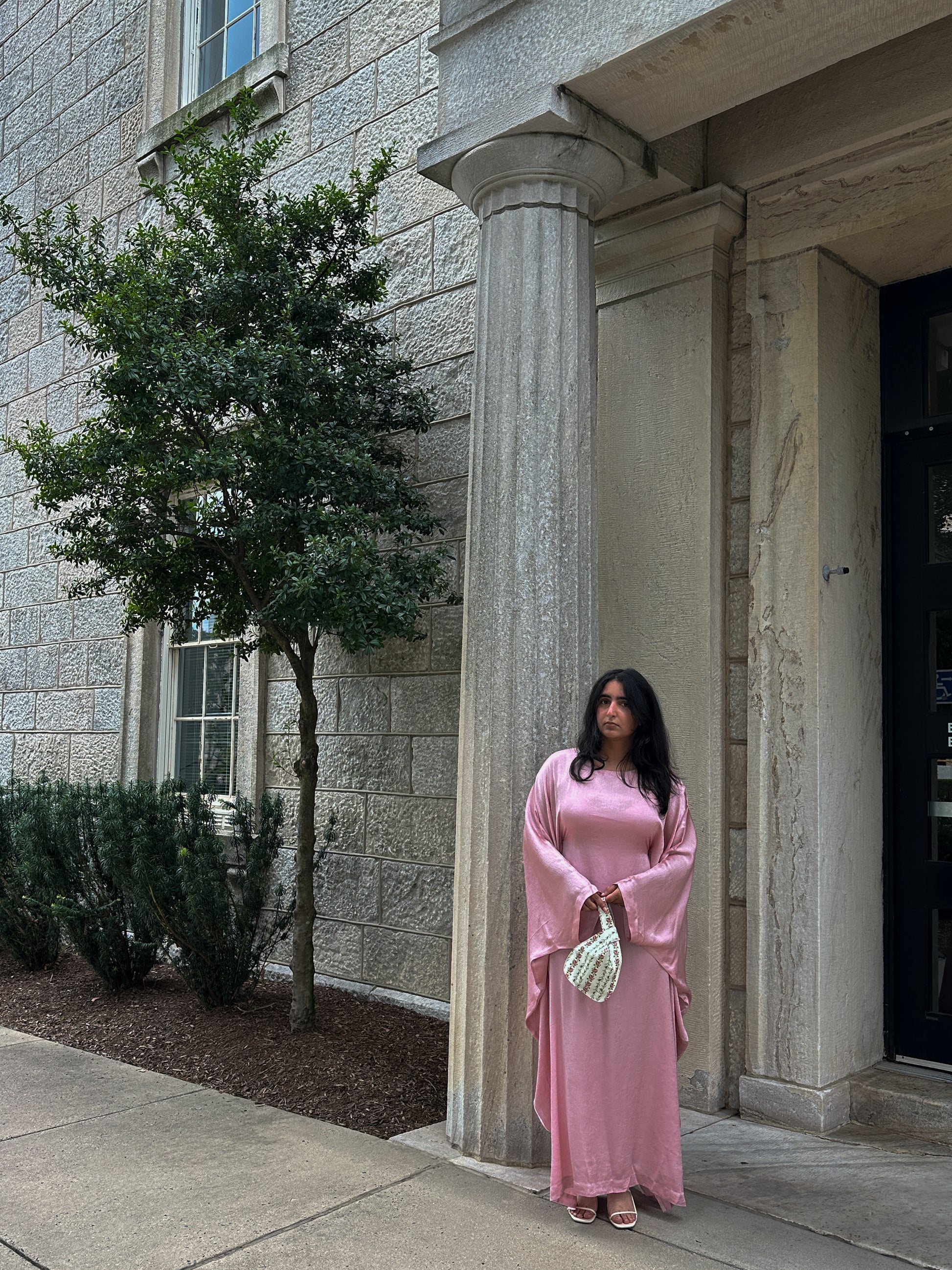 Woman in a pink dress standing outside a stone building