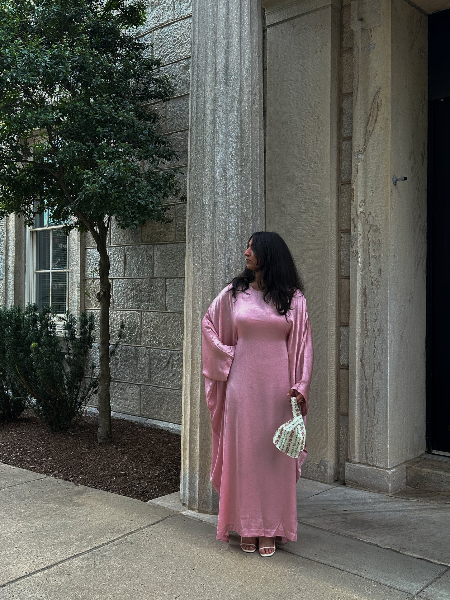 Woman in a pink dress standing outside a building