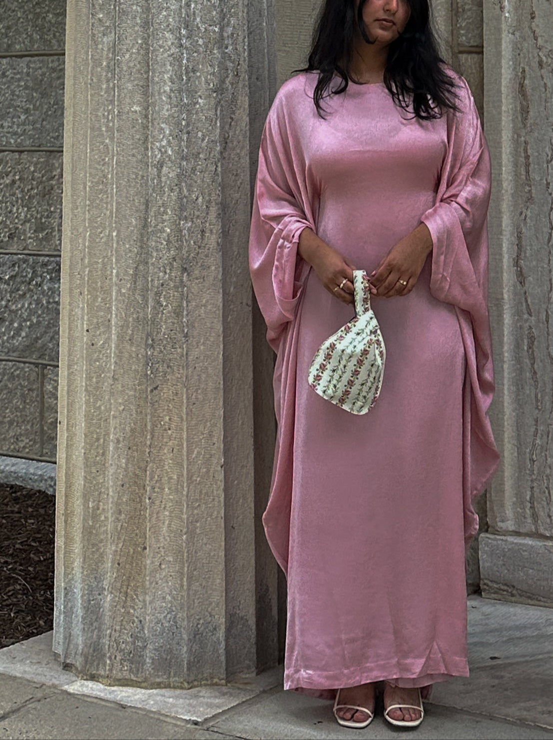 Woman in a pink dress standing against stone columns