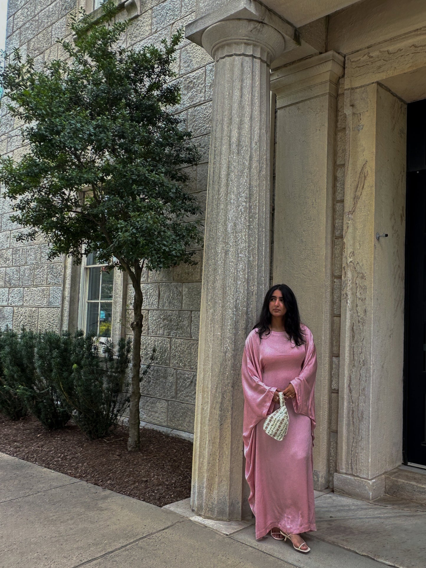 Woman in a pink dress standing outside a building with columns
