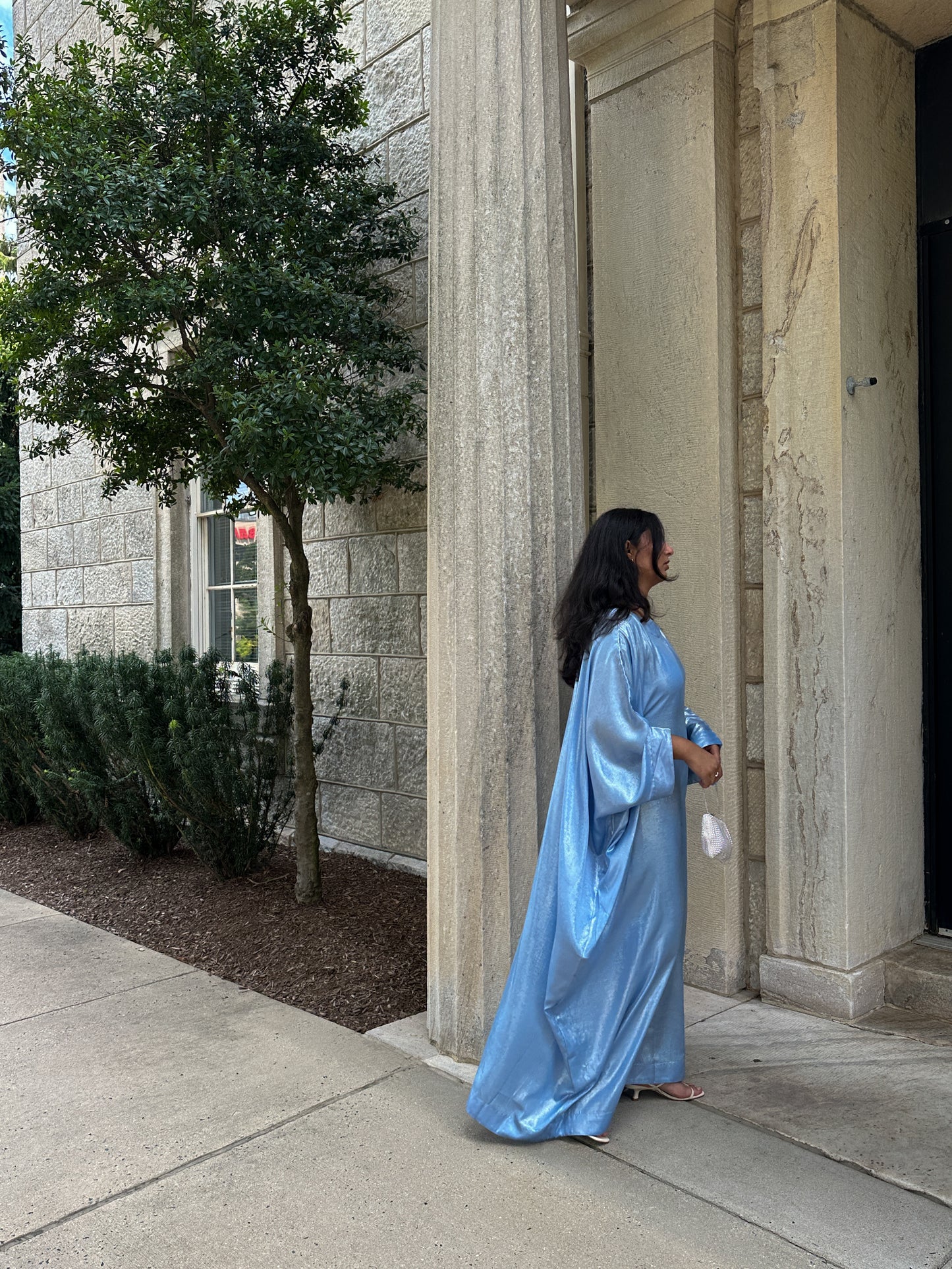 Person in a blue gown standing outside a building with columns