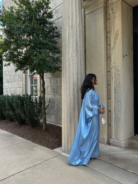 Person in a blue gown standing outside a building with columns