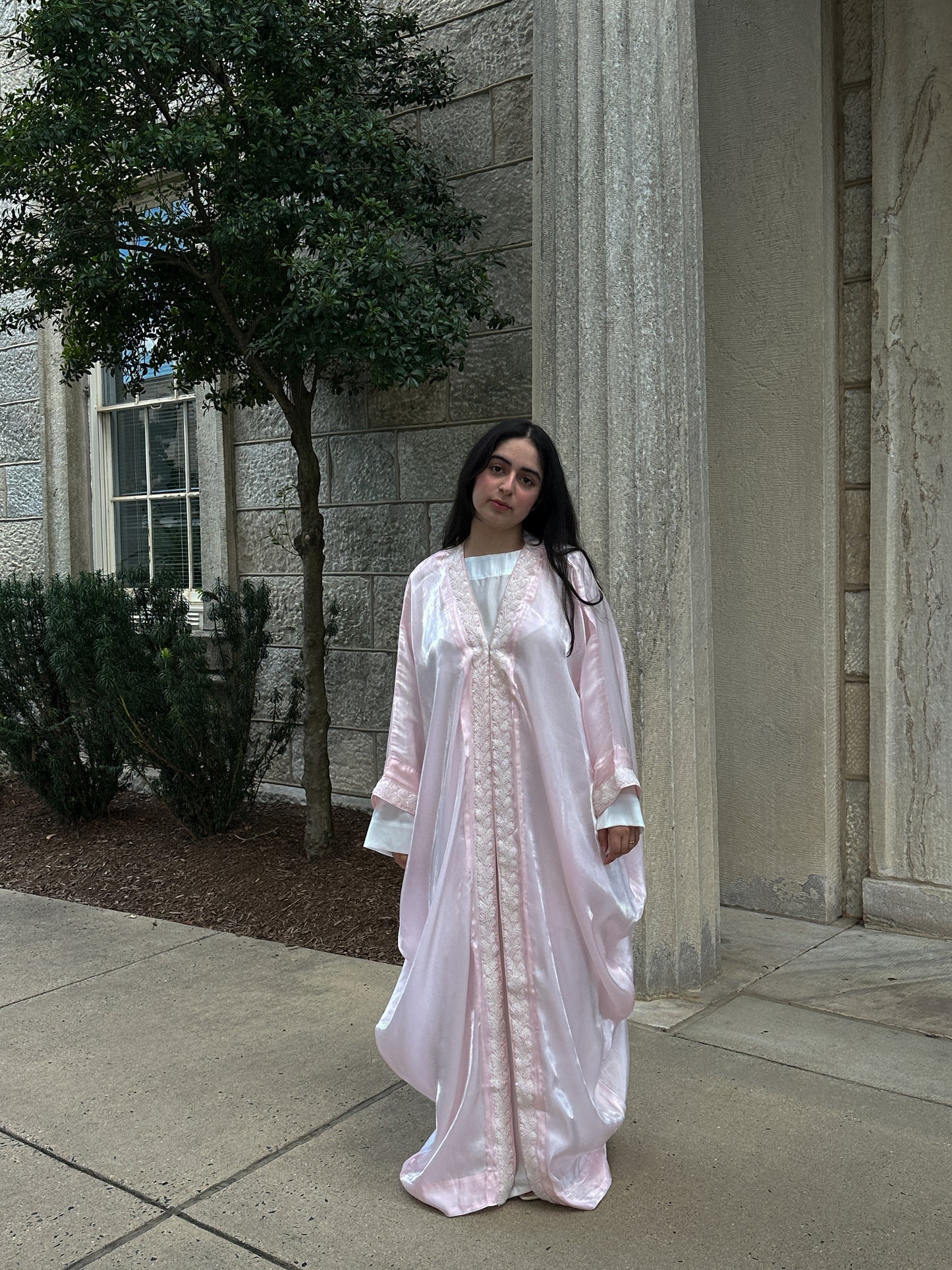 Woman in a light pink dress standing outdoors near a building