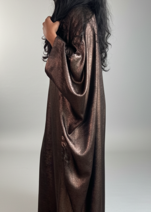 Person wearing a long, dark brown satin dress against a white backdrop