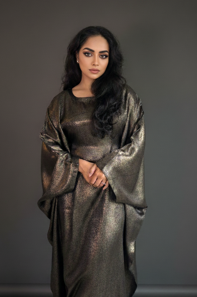 Woman wearing a metallic abaya against a gray background