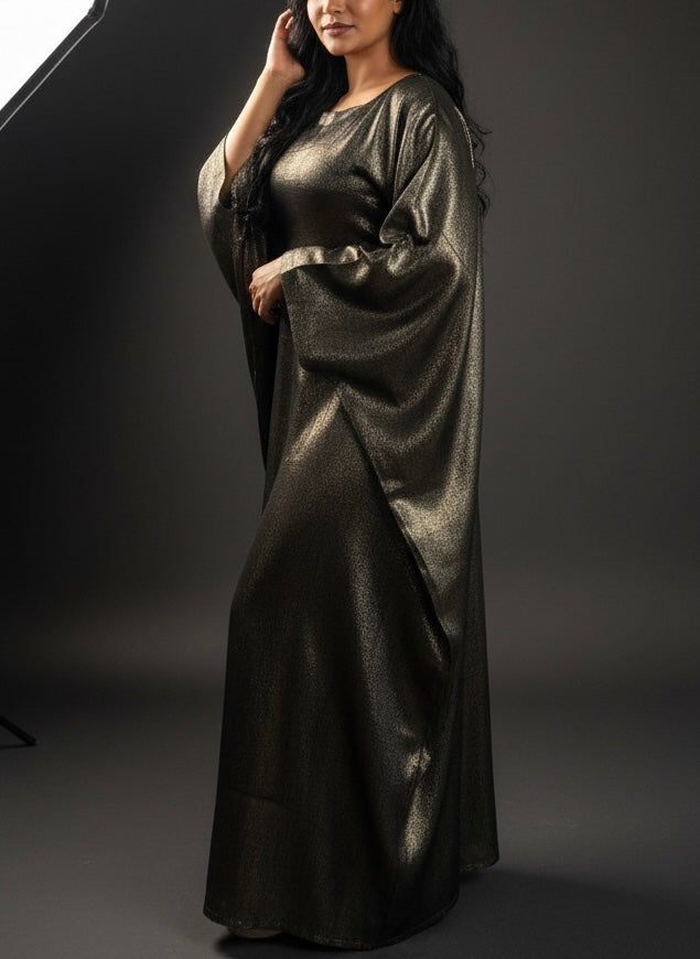 Woman wearing a long, dark metallic abaya against a gray background