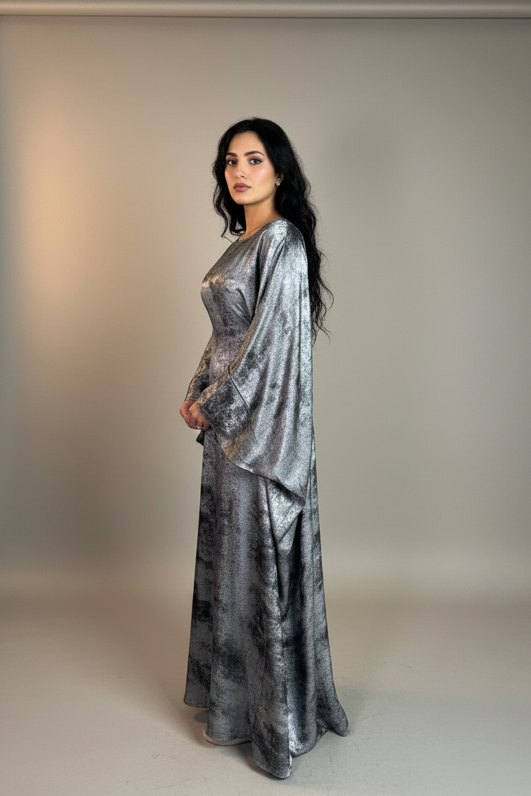 Woman wearing a silver abaya against a neutral background