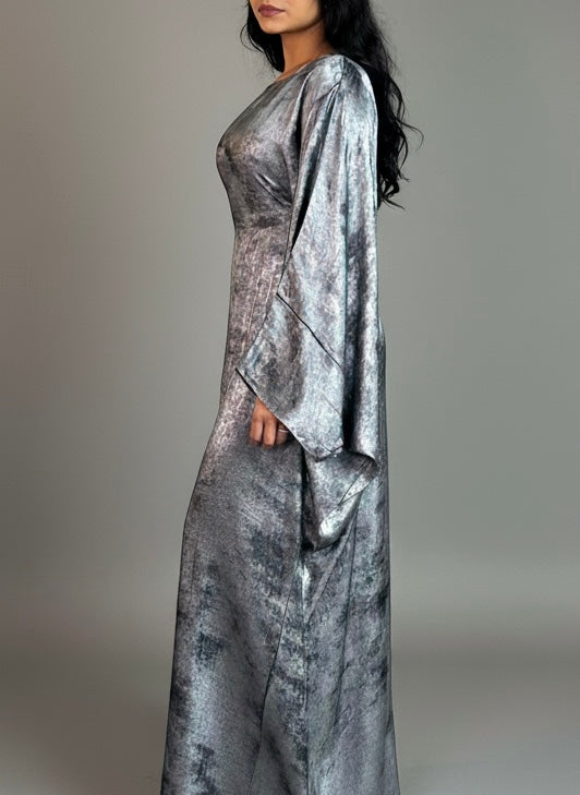 Woman wearing a silver metallic abaya against a gray background