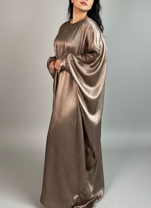 Woman wearing a metallic bronze abaya against a plain background