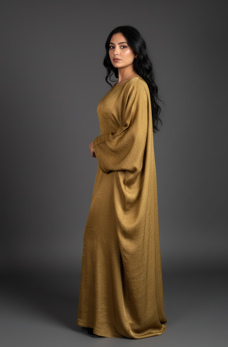 Woman wearing a long, flowing mustard yellow abaya against a gray background