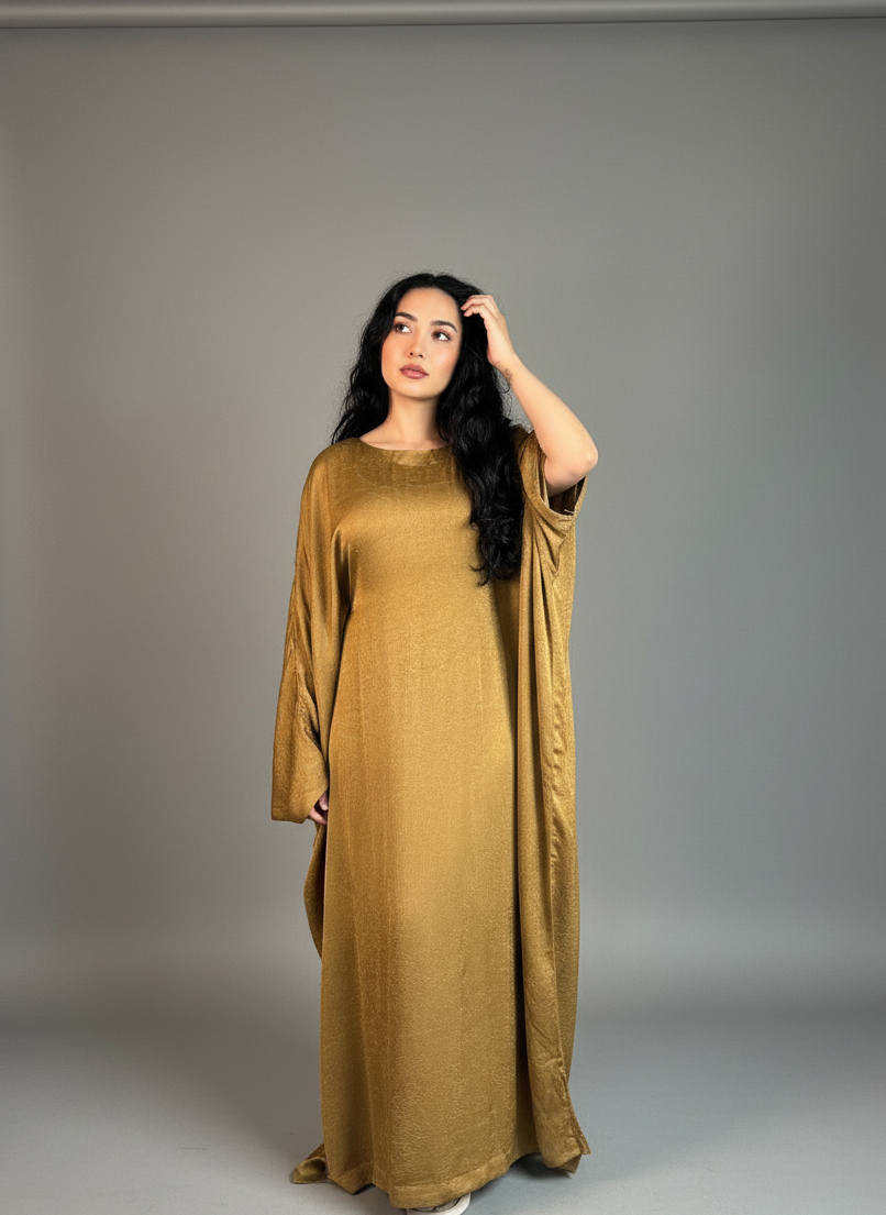 Woman wearing a long mustard yellow abaya against a plain background