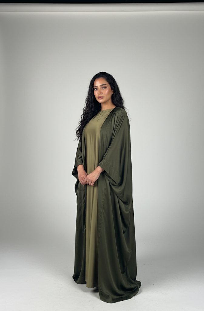 Woman wearing a long, green dress with a plain background