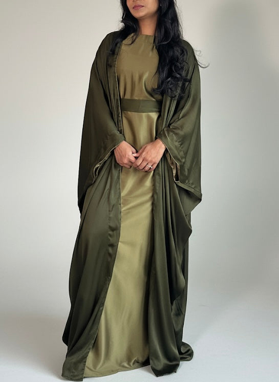 Woman wearing a long olive green dress with a matching shawl on a white background