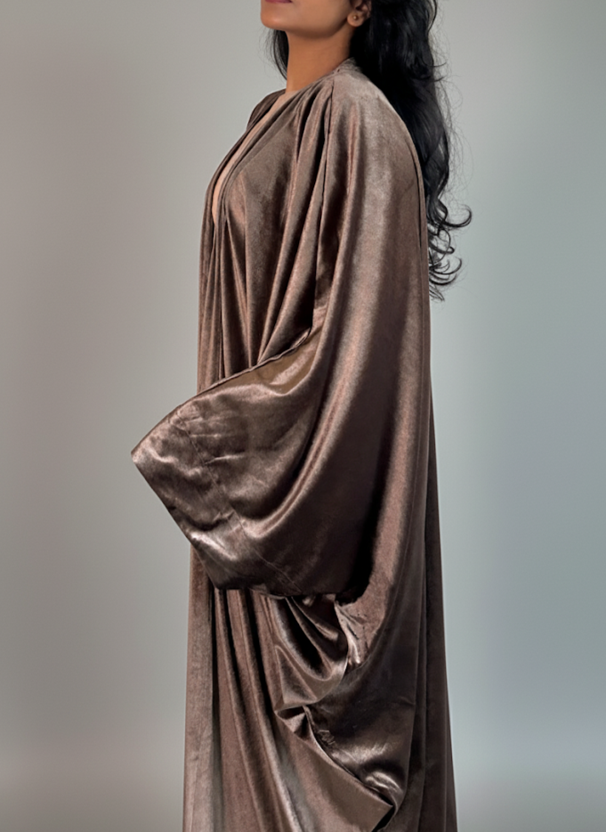 Woman wearing a flowing brown dress against a gray background