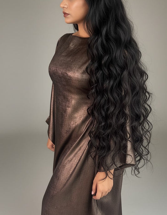 Woman wearing a metallic brown dress with long, wavy hair on a neutral background