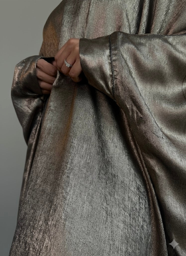 Close-up of a metallic silver garment with a hand adjusting the fabric against a neutral background