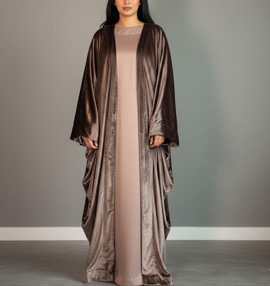 Woman wearing a long, flowing dress with a matching shawl against a gray background