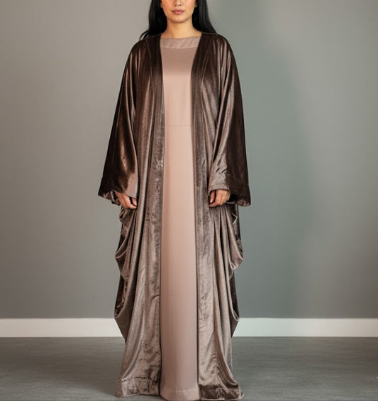 Woman wearing a long, flowing dress with a matching shawl against a gray background